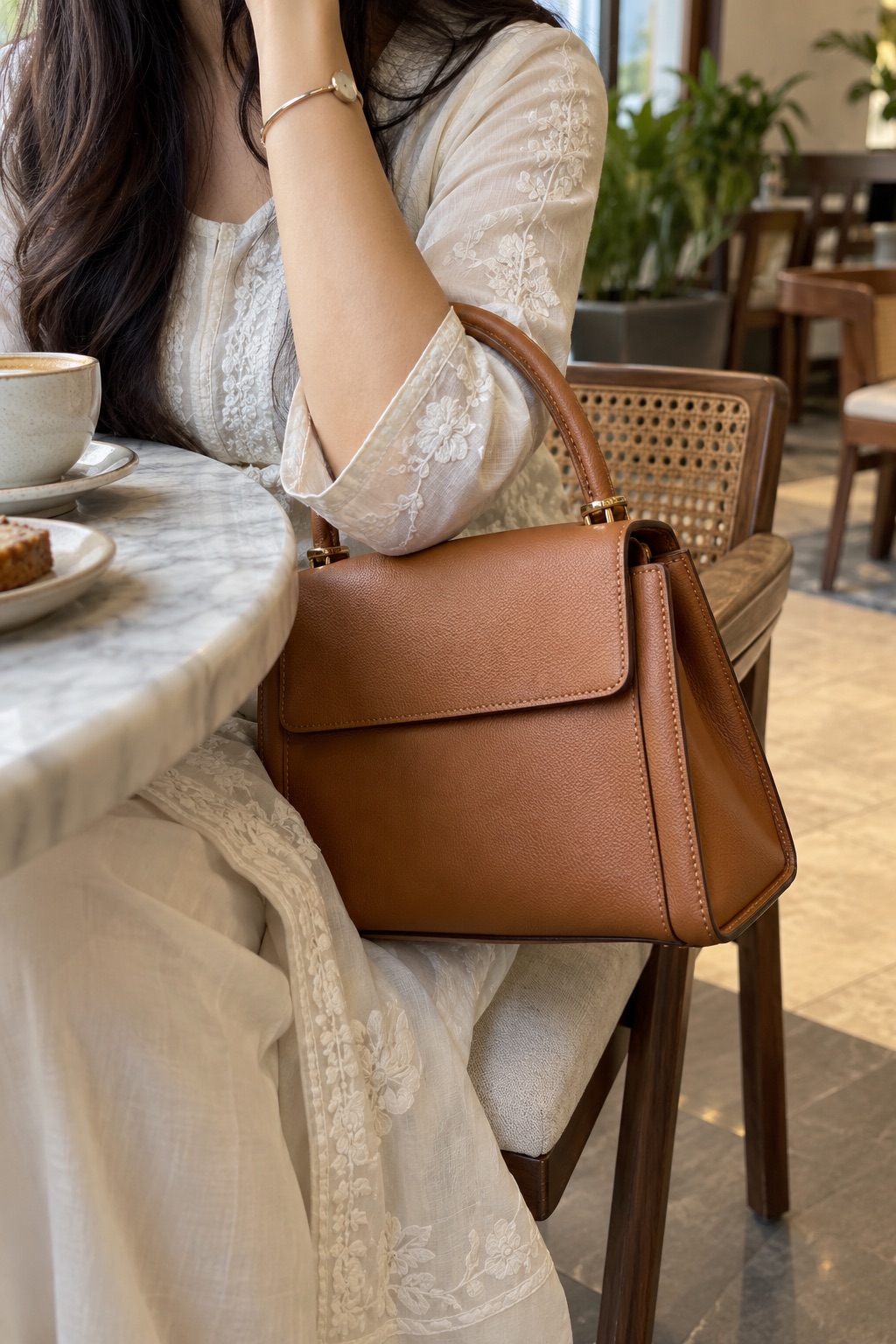 A tan top-handle bag at a café.